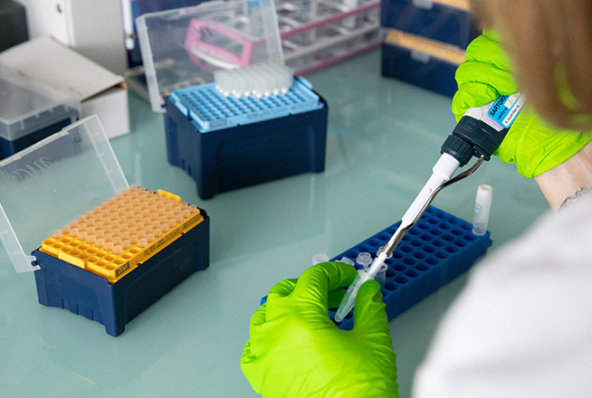 Une chercheuse manipule des pipettes dans un laboratoire.