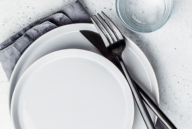 Assiette et plats vides disposés sur une table.